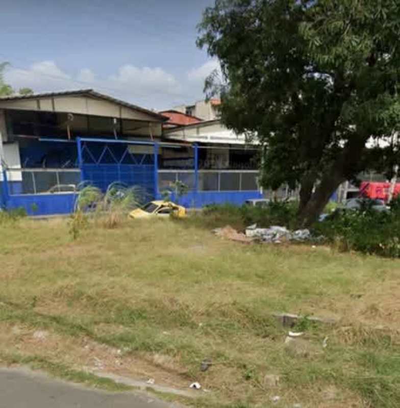 Industrial property with blue fence, large open yard, and mature tree in Río Abajo Pedregal Panama City