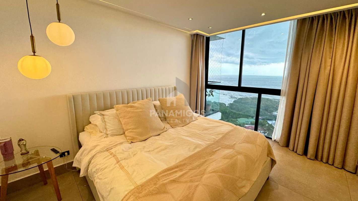 Sleek bathroom with glass enclosed rainfall shower and ocean view window in Panama apartment