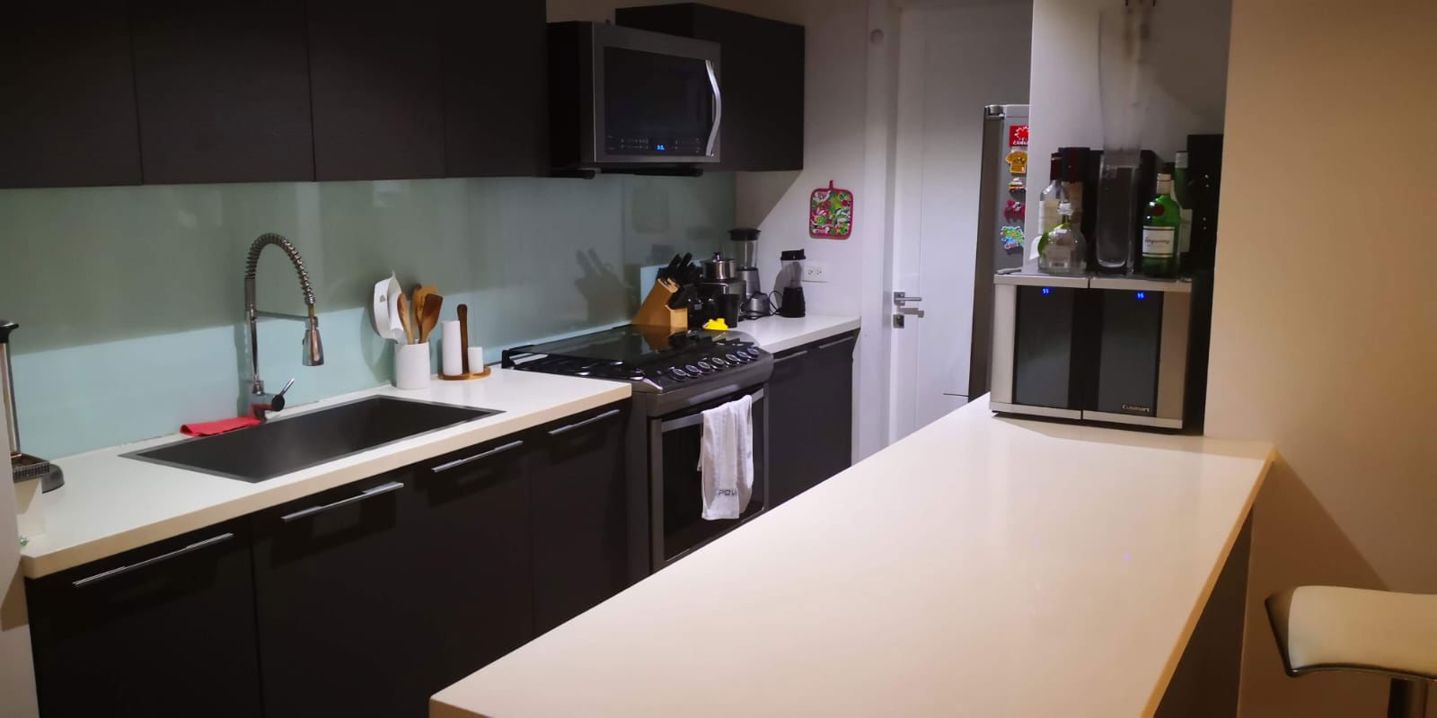 Modern open kitchen with island, glass backsplash, and stainless appliances PH YOO Panama Avenida Balboa