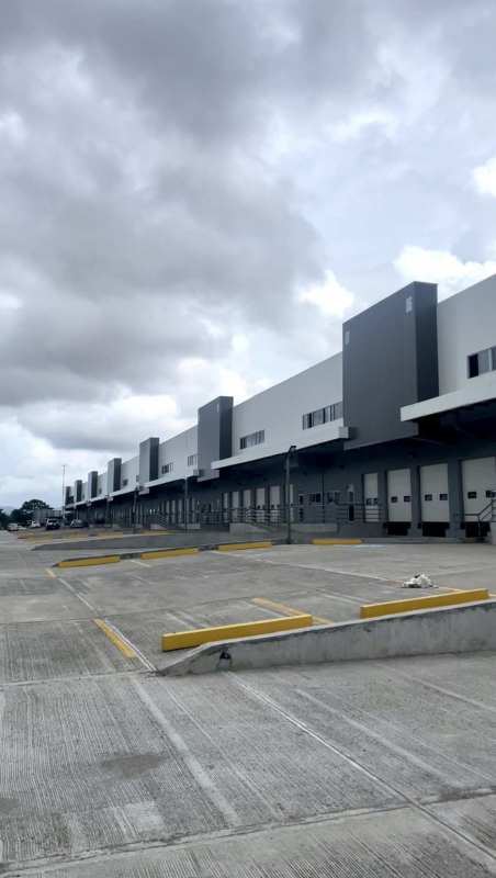 Modern industrial warehouse facade with multiple roll-up doors and large parking area