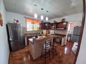 Traditional style kitchen with island, wood cabinetry, tiled backsplash in Penonomé house