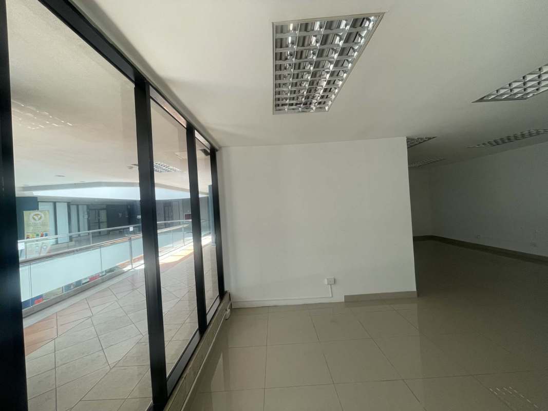 Empty 75m² office space with large indoor windows overlooking shopping corridor in Dorado Mall Panama City