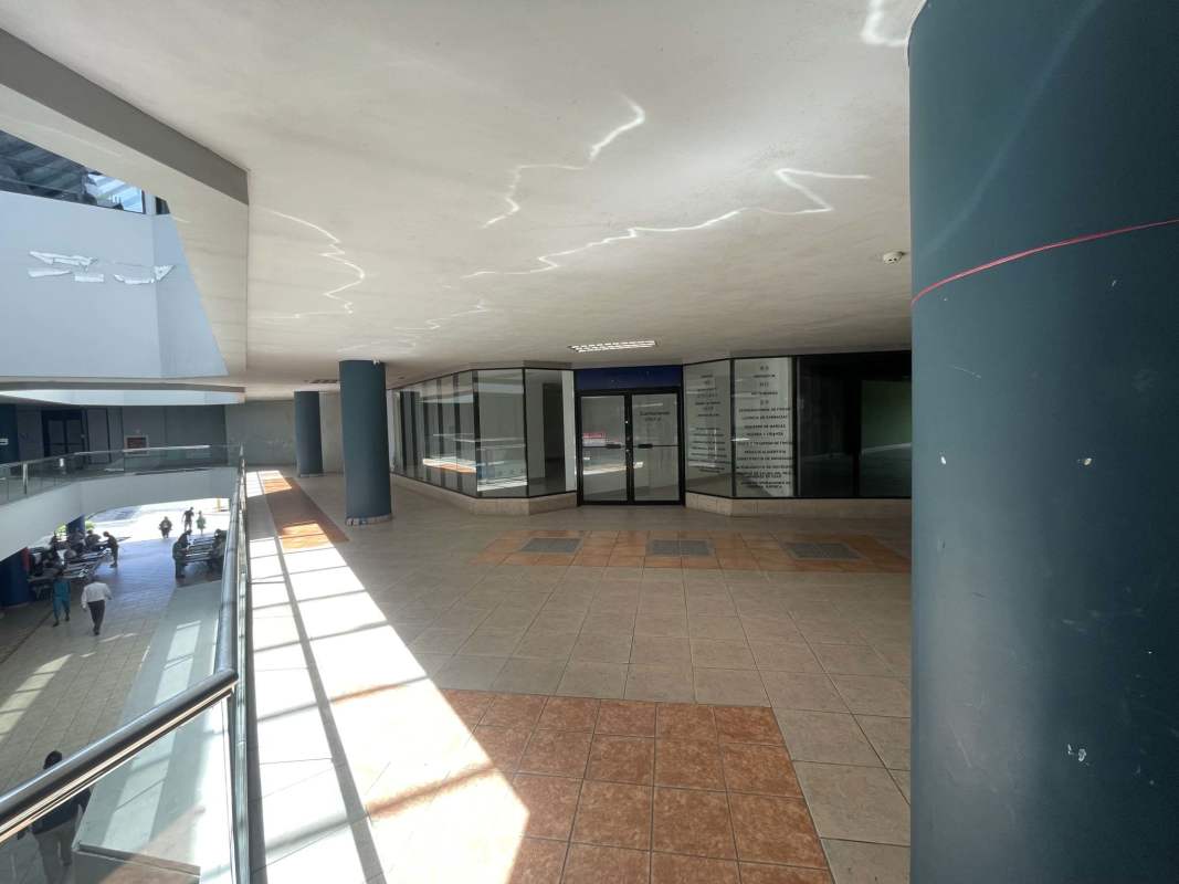 Modern commercial corridor with glass storefronts and elevator lobby inside Dorado Mall Panama