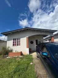 Simple bedroom with tile flooring, natural light and window curtains in affordable Playa Leona house