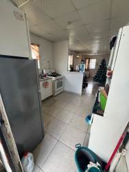 Basic open kitchen with refrigerator, stove, tile flooring in affordable Playa Leona house for sale