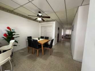 Dining area with table, chairs, fan, and corridor leading to bedrooms in Santa Rana Chitré house for sale