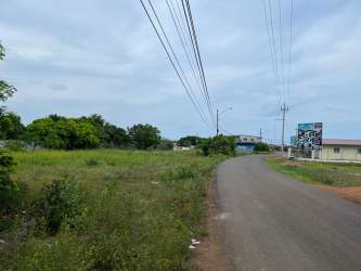Vacant roadside lot with power lines and adjacent commercial building in Chitré Panama