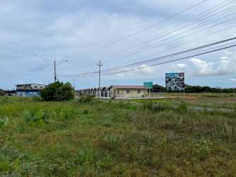 Vacant lot with billboard and single story building roadside view in Chitré Panama
