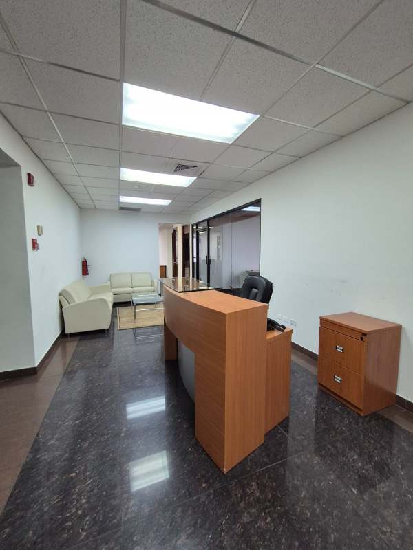 Reception area with wooden desk, cream sofas, glass coffee table, marble flooring inside Banco General Tower Panama