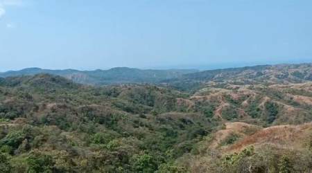 Wide panoramic view of mountains, green hills, ocean in distance rural Panama countryside