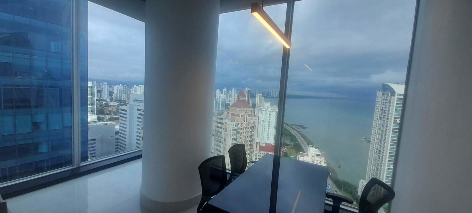 Boardroom with panoramic floor-to-ceiling glass windows and conference chairs in PH Oceania Panama