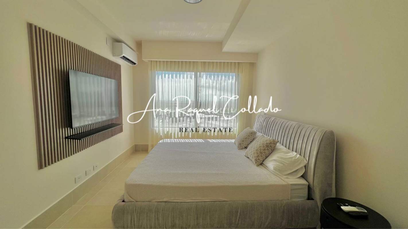 Bright bedroom with gray upholstered bed, TV, AC at PH Ocean House Santa Maria Panama