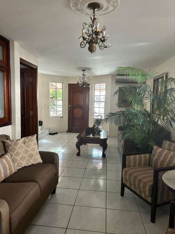 Spacious living room with large windows, beige leather sofas and tiled floors at house in Condado del Rey Panama