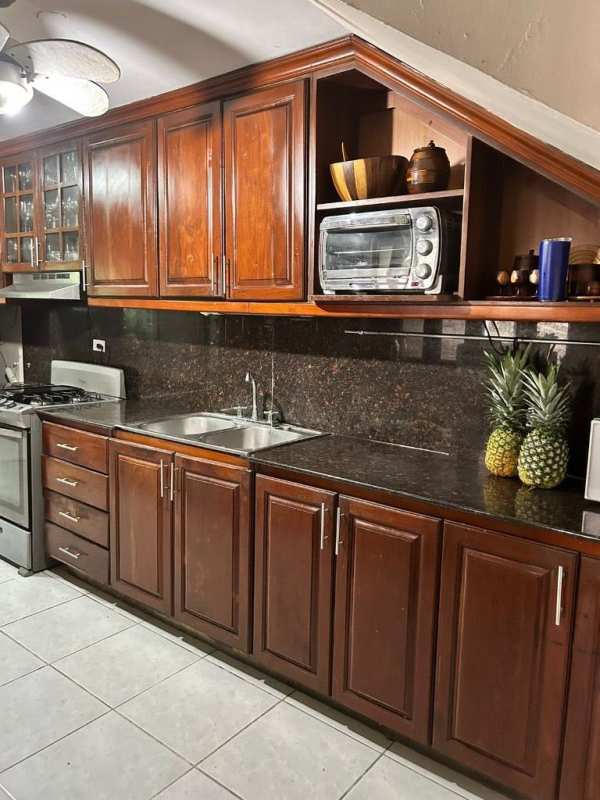 Spacious kitchen with wooden cabinetry, granite countertops, gas stove in Condado del Rey Panama house for sale