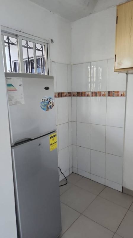 Kitchen with refrigerator, ceramic tiles, window grill, and upper cabinets in apartment Edificio Z-3 Panama