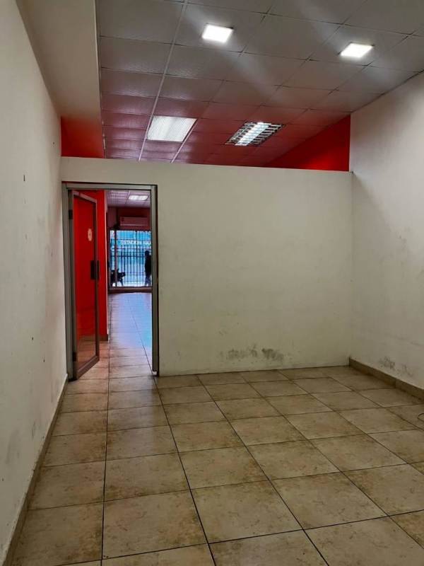 Open tiled commercial space with red walls and ceiling lights at Jardines del Hotel Panama Vía España
