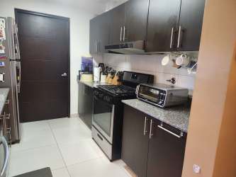 Modern kitchen with granite countertops, dark cabinets and appliances in Panama Pacifico townhouse for sale