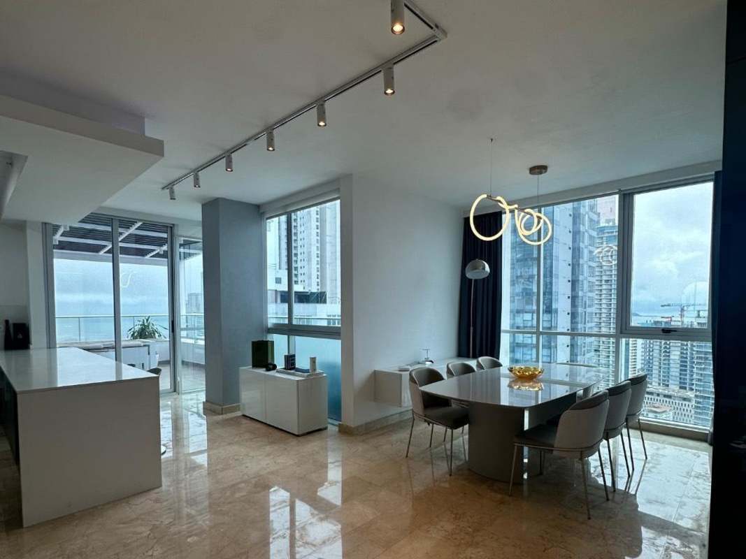 Open-plan living and dining area with marble flooring, staircase and ocean skyline views in PH Bicsa Financial Center Panama