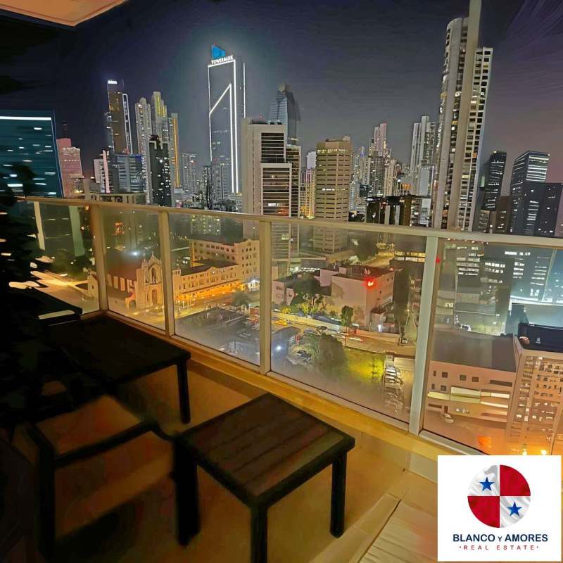 Balcony with glass railing overlooking Panama City skyline at night PH Blanco y Amores