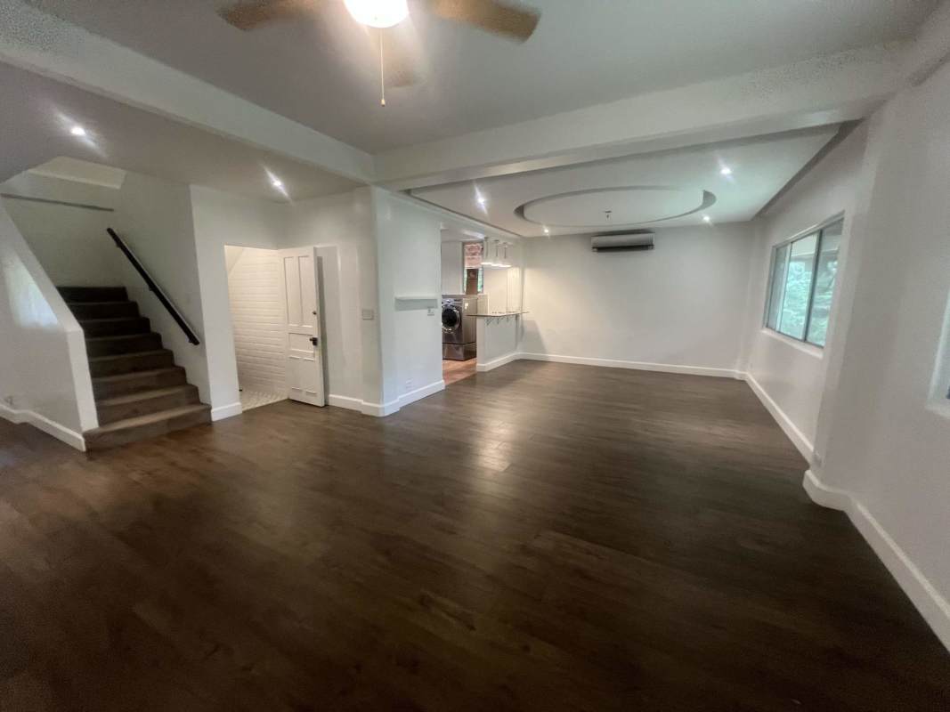 Open bright living room with wood floors, ceiling detail, staircase, and garden views in Clayton Panama