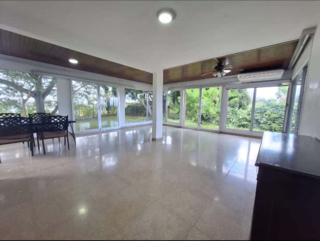 Spacious enclosed sunroom with AC, dining area, ceiling fan and large windows overlooking garden El Dorado Panama