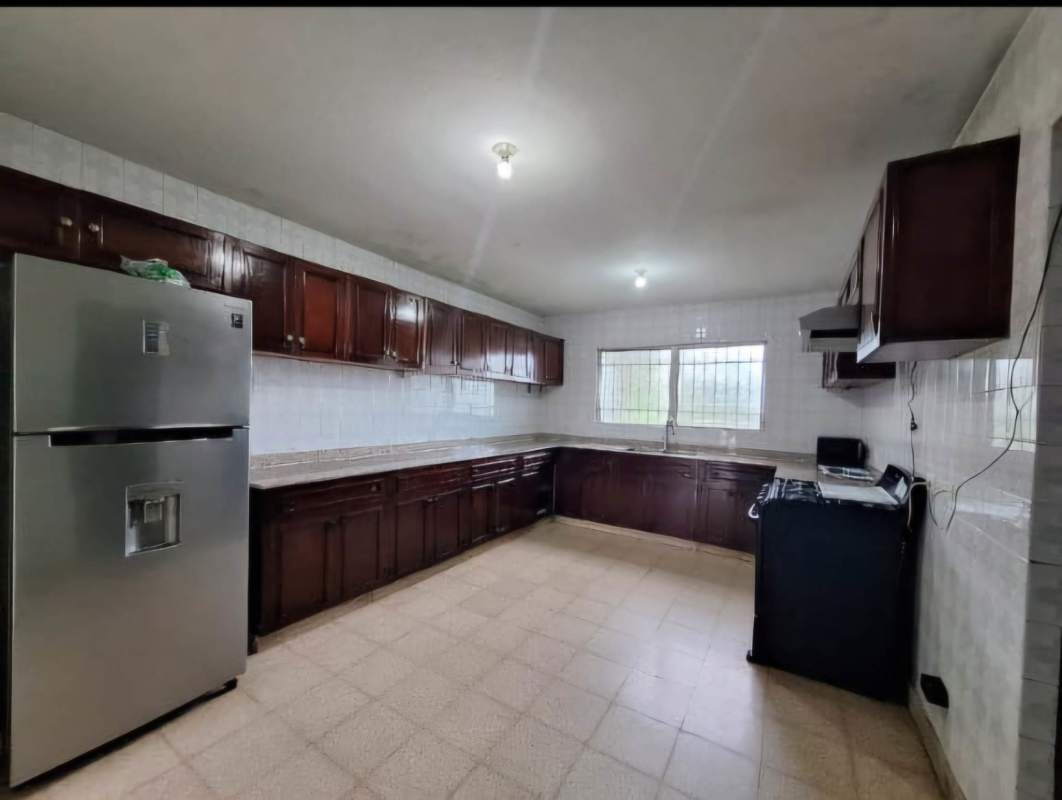 Spacious traditional kitchen with wood cabinets, granite countertops, large window, refrigerator and stove in El Dorado house Panama