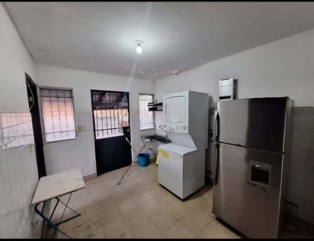 Covered outdoor patio with brick columns, white metal dining set and garden view at villa in El Dorado Panama