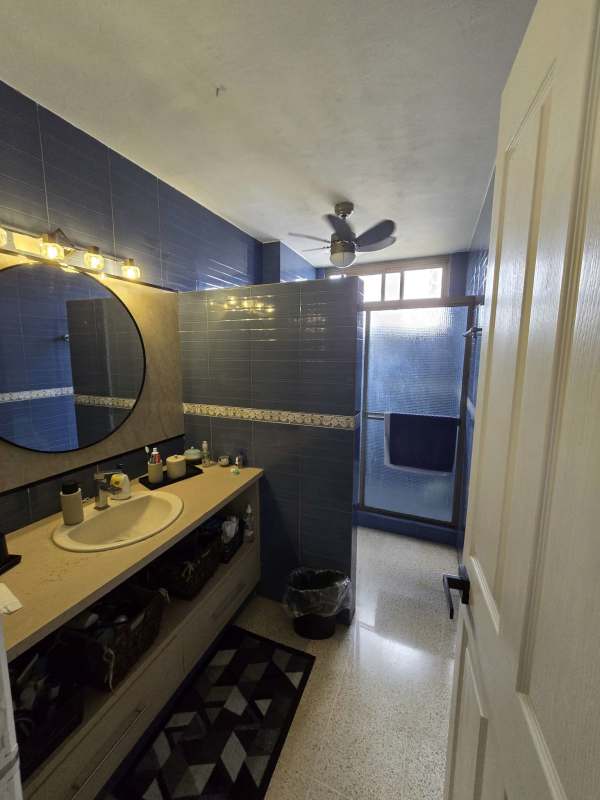 Bathroom with blue tiles, glass shower, round mirror, and modern fixtures in PH Vista Hermosa Panama