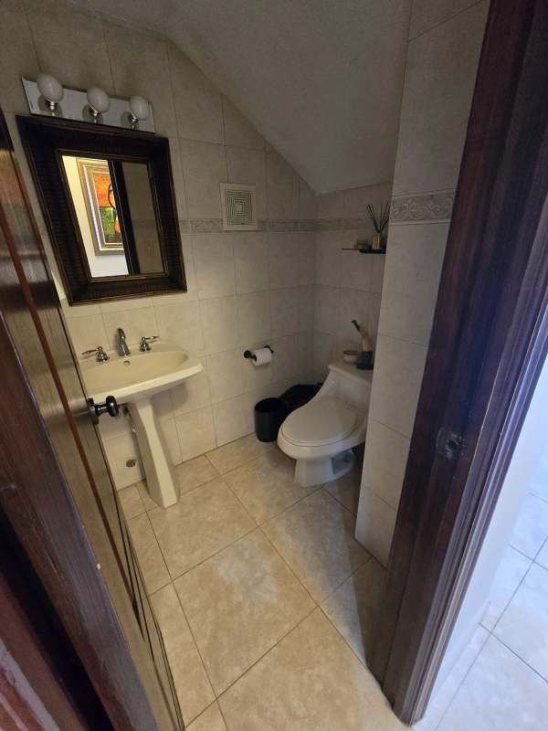 Modern bathroom with glass shower, beige tile walls and floor, large mirror in Costa del Este Panama house