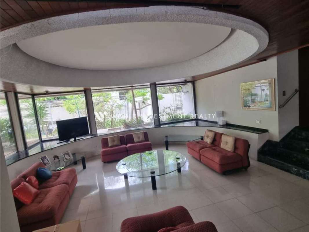 Sunken living room with curved windows, red sofas and marble flooring in Bella Vista home
