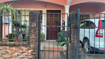 Gated house outside with carport, arched porch, potted plants in Alborada Colón Panama