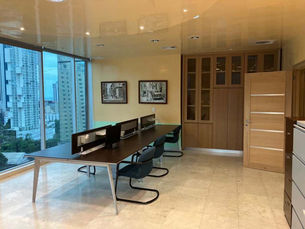 Modern shared work desk area with floor-to-ceiling windows and cabinets in banking area Panama