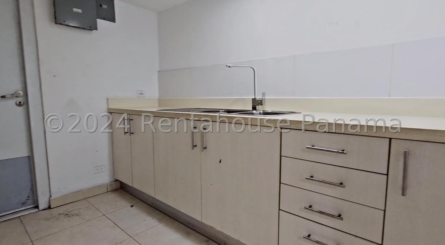 Light cabinetry kitchen area with double stainless sink and ceramic backsplash