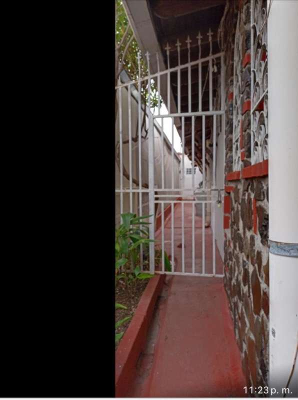 Red walkway, secured gate and stone wall facade outside room rental in San Antonio Panama