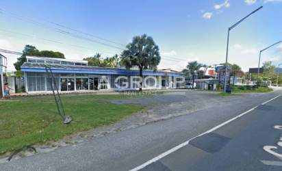 Angle exterior shot of shopping plaza in Nueva Gorgona with palm trees, signage and parking lot on highway