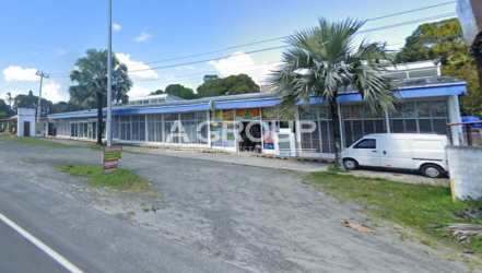 Commercial plaza front showing retail glass storefronts, parking, and highway access in Nueva Gorgona Panama
