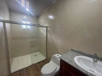Modern bathroom with granite countertop, glass shower and ceramic sink in Las Lajas villa Panama