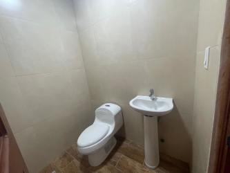 Simple bathroom with white fixtures and tan tiles in Las Lajas Panama estate for sale