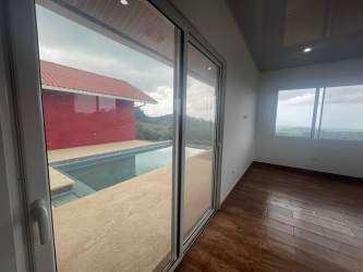 Spacious living room with large glass doors viewing pool and countryside at Las Lajas Panama