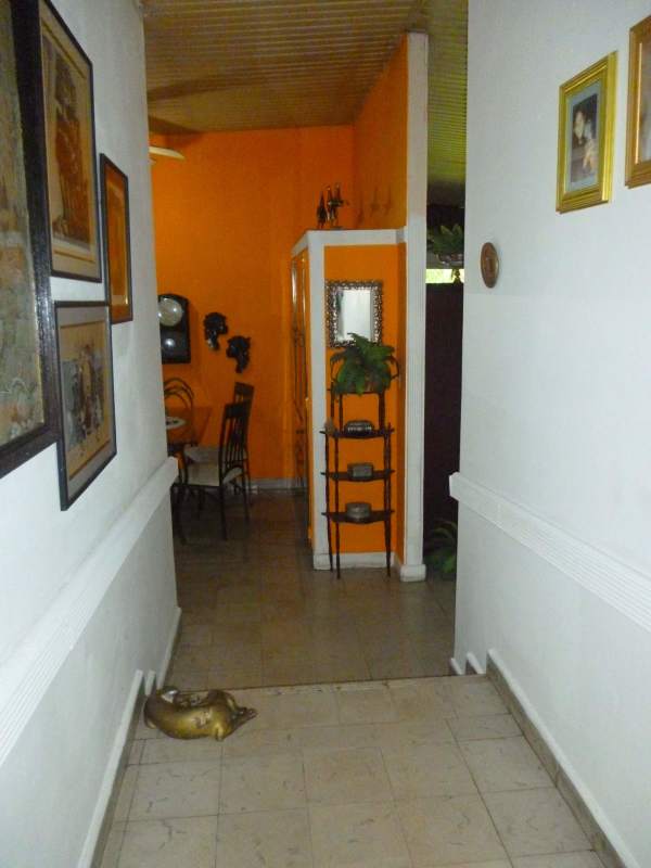 Hallway with orange accent wall leading to dining room with wall art in exclusive Panama house