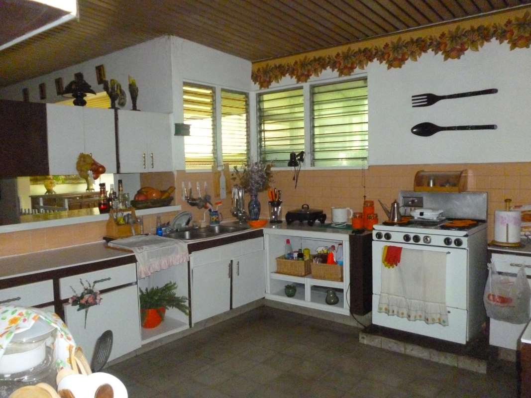 Retro kitchen with vintage stove, large windows, wood ceiling and ample cabinetry in Panama luxury home