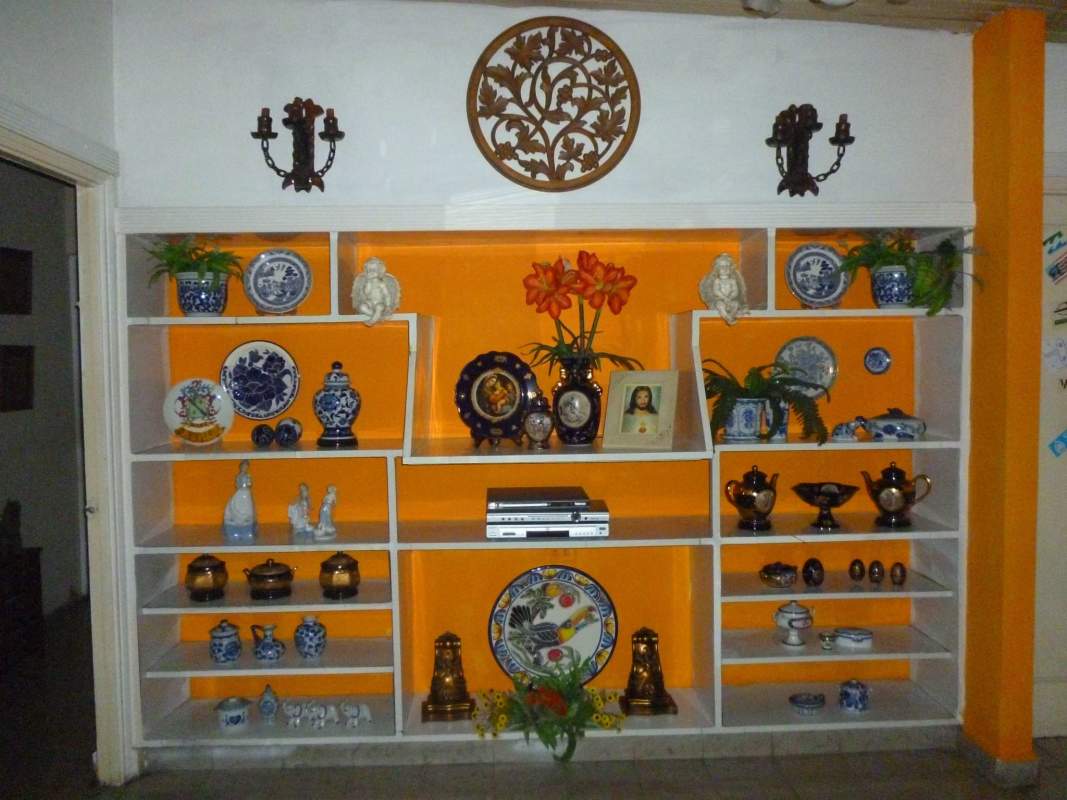 Interior wall with built-in shelving decorated with ceramics, photos and plants in luxury Panama home