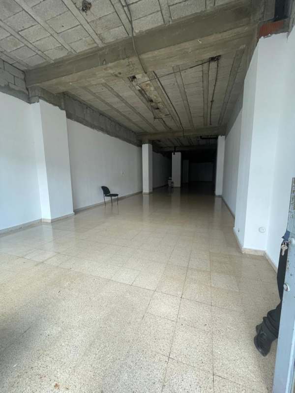 Empty commercial interior space with tiled floor, exposed beams, glass door on busy Transístmica Avenue, Panama City