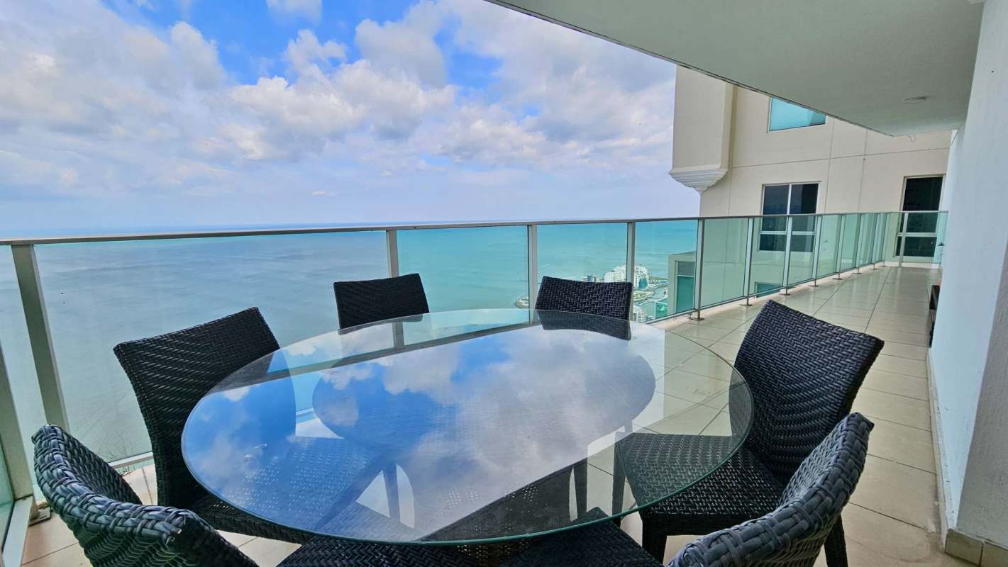 Large living and dining area with panoramic windows and ocean views at Oasis on the Bay