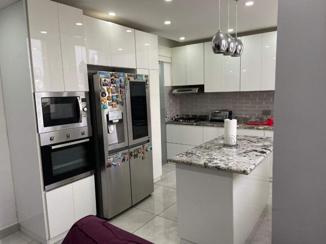 Kitchen with granite island, stainless appliances and Subway tile backsplash in Panama City apartment