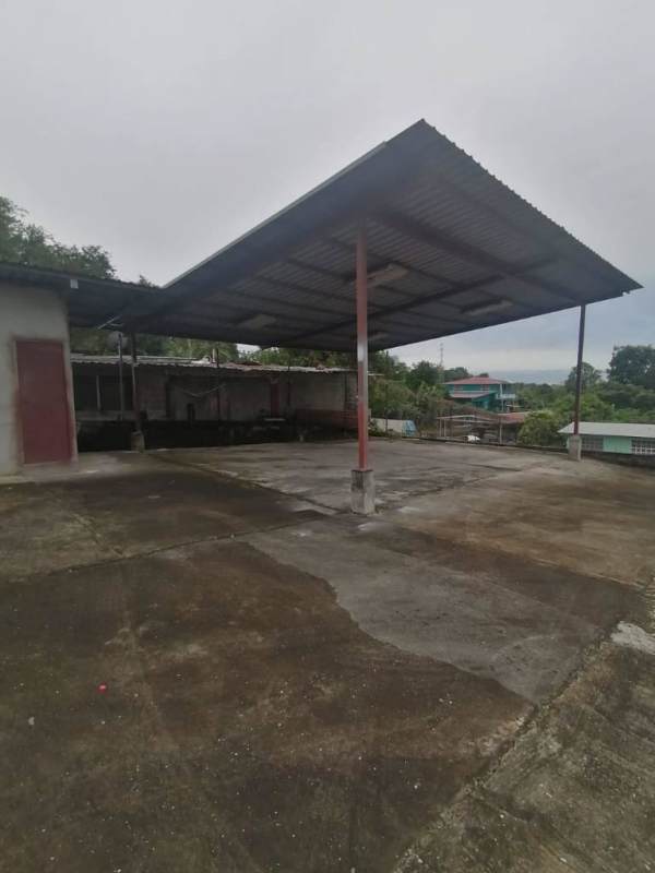 Concrete paved lot with partially covered metal roof shelter within secured boundary wall Panama