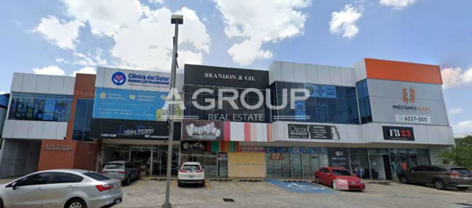 Facade of two-story commercial building with retail units, large windows, and parking at Galería Cincuentenario Juan Díaz Panama