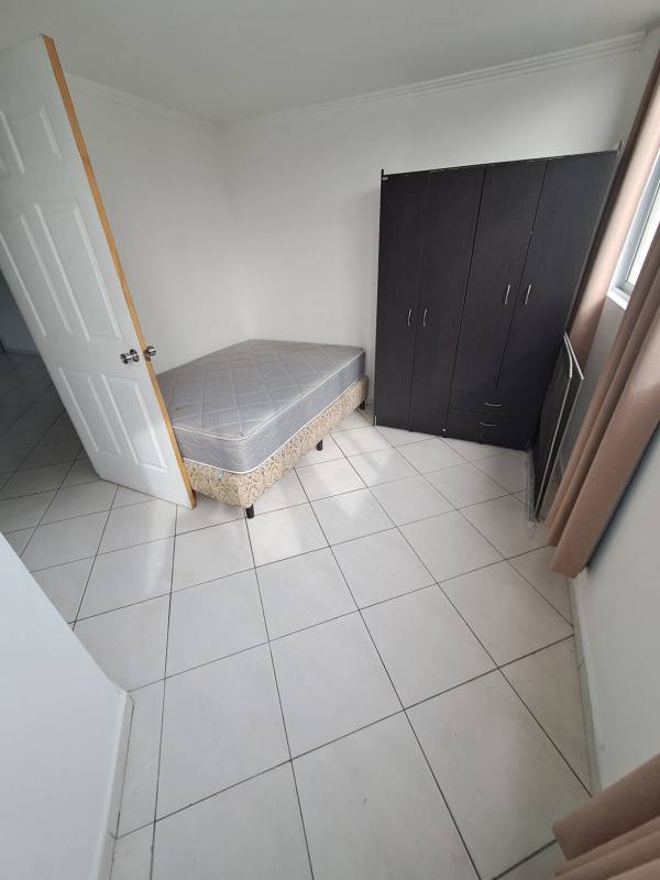 Minimalist bedroom with single bed, window with curtain in Panama City apartment