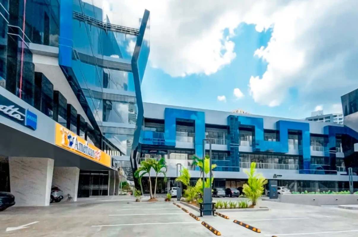 Commercial plaza exterior with blue glass walls and large parking area Via Brasil Panama