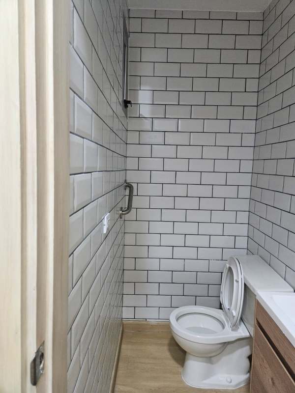 Small bathroom with white tiles, toilet, vanity cabinet inside medical office